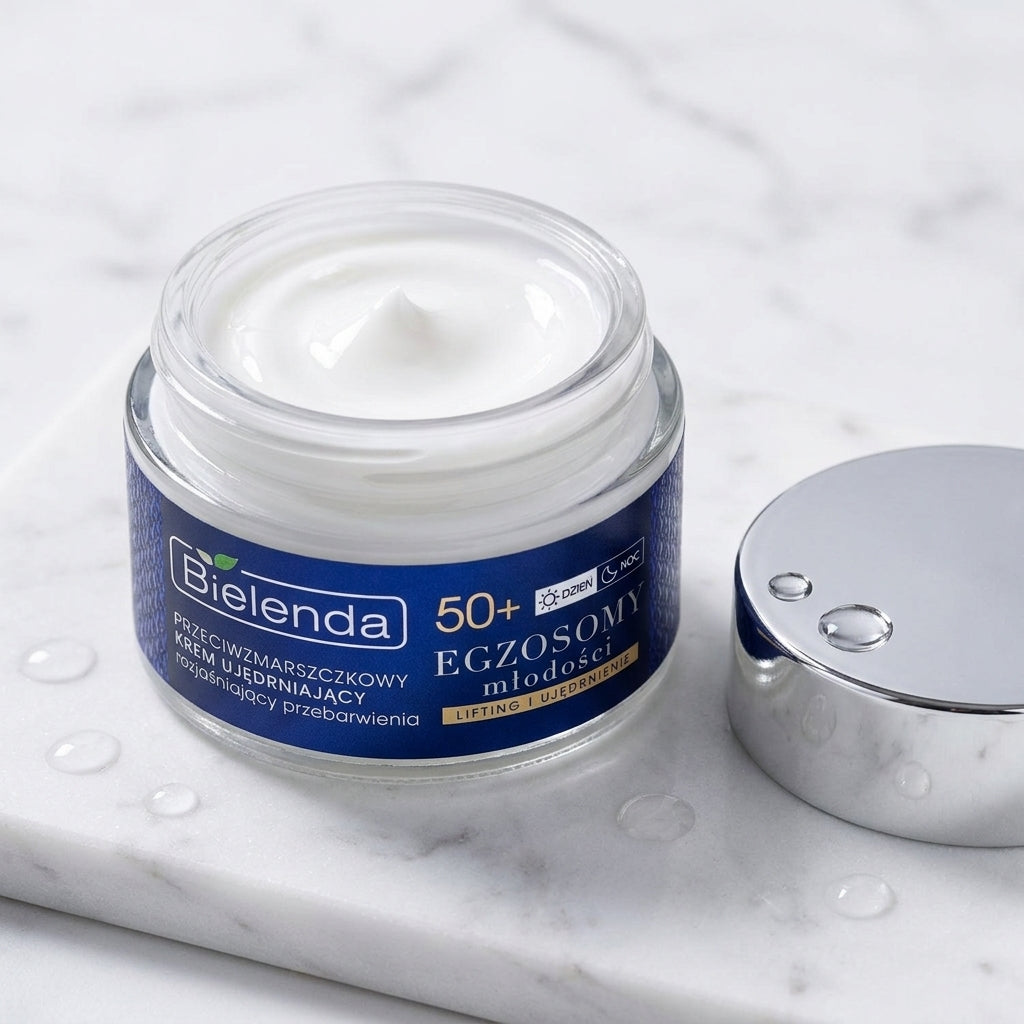Open jar of Bielenda Exosomes of Youth cream displaying its rich white texture on a white marble surface
