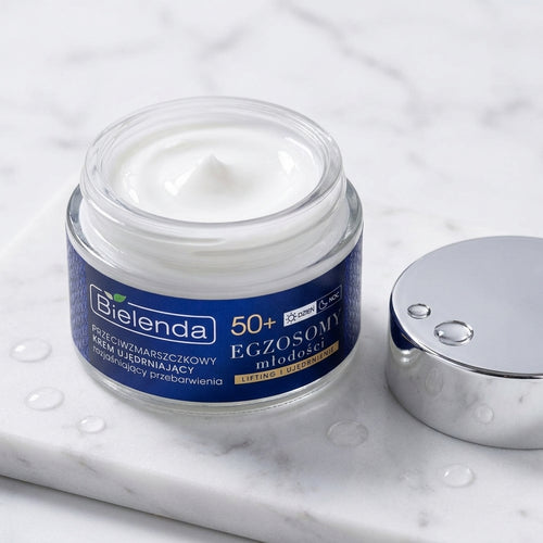 Open jar of Bielenda Exosomes of Youth cream displaying its rich white texture on a white marble surface
